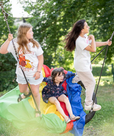 Kinder im sonnigen grünen Garten auf einer Schaukel
